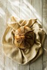 Top view of freshly baked round loaf of bread on tea towel. — Stock Photo