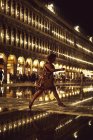 Frau springt nachts über beleuchtete Markierungen in Venedig, Italien. — Stockfoto