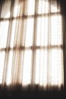 Primer plano de la luz solar filtrándose a través de la cortina de red frente a la ventana de vidrio con plomo . - foto de stock