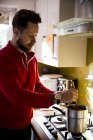 Uomo in piedi in cucina domestica e mescolando cera di candela . — Foto stock