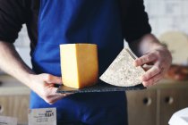Queijeiro segurando ardósia exibindo dois queijos diferentes — Fotografia de Stock