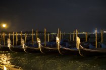Illuminated gondolas moored in Canale Grande in Venice, Italy, at night and view across water lagoon — Stock Photo