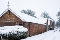 Exterior view of red brick cottages with snow-covered roofs along rural road. — Stock Photo