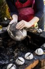 Close-up of ceramic artist sitting next to outdoor smoke fire pit and working on vase. — Stock Photo