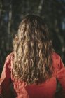 Вид сзади на девочку-подростка с длинными волнистыми каштановыми волосами, стоящую на улице — стоковое фото