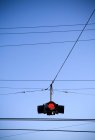 Arrêter la lumière rouge et les fils de transport contre le ciel bleu — Photo de stock