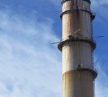Smokestack of industrial plant against blue sky with clouds, cropped with detail — Stock Photo