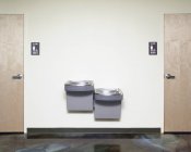 Drinking fountains near male and female restrooms doors — Stock Photo