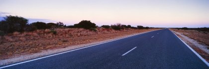 Vazio dois estrada faixa ao amanhecer no campo árido — Fotografia de Stock