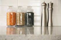 Кухонный стол с банками бобовых и соленых и перцовых шейкеров — стоковое фото