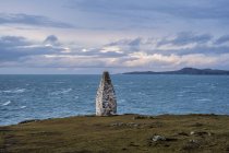 Bahía de Cardigan y cairn de piedra que marca la entrada al puerto de Porthgain desde Pembrokeshire Coast Trail, Parque Nacional de Pembrokeshire, Gales, Reino Unido . - foto de stock