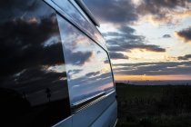 Reflection of clouds on camper van window at sunset. — Stock Photo