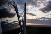 Reflexão de nuvens na janela van campista ao pôr do sol . — Fotografia de Stock