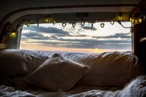 Wohnmobil mit Kissen und Lichterketten, Blick durch die Heckscheibe bei Sonnenuntergang. — Stockfoto