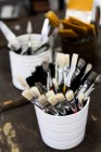 Close-up of white ceramic pots with selection of paintbrushes in various sizes. — Stock Photo