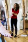 Primo piano del piede femminile nudo con unghie dei piedi verniciate rosse e artista che lavora in background . — Foto stock