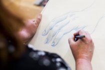 High angle close-up of artist drawing hand in art class. — Stock Photo