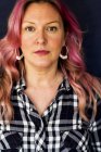 Портрет жінки з довгим хвилястим волоссям з рожевими смугами в чорно-білій картатій сорочці і кільцевих сережках . — стокове фото