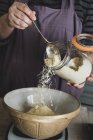 Midsection de pessoa derramando açúcar em tigela de mistura com ingredientes de cozimento . — Fotografia de Stock