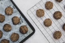 Vista de ángulo alto de galletas de chocolate recién horneadas en bandeja para hornear y estante de enfriamiento . - foto de stock