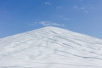 Manure heap covered with white tarpaulin against blue sky. — Stock Photo