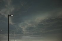 Nuages de tempête dramatiques approchant des lampadaires en ville — Photo de stock