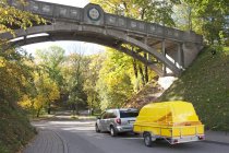 Van towing yellow trailer on road in Tartu, Estonia — Stock Photo