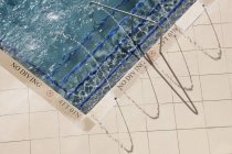 Escaleras de la piscina en el agua con barandilla y ninguna señal de advertencia de buceo - foto de stock