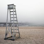 Empty lifeguard chair and wooden pier in fog, Panama City Beach, Florida, USA — Stock Photo
