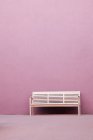 White bench in front of pink wall of building — Stock Photo