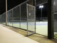 Puerta abierta a la entrada de la cancha de tenis por la noche - foto de stock