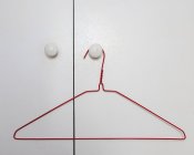 Cintre en fil rouge suspendu à la poignée de porte de la porte blanche — Photo de stock