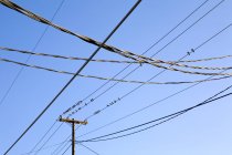 Strommasten und Stromleitungen vor blauem Himmel mit Vögeln bedeckt — Stockfoto