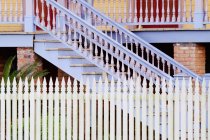 Stairs and white picket fence of brick building — Stock Photo