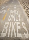 Bicicleta pista com letras na praia de areia com pegadas — Fotografia de Stock