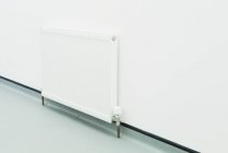 Weißer Heizkörper gegen schlichte Wand im Raum — Stockfoto