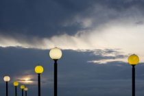 Round street lights illuminating at dusk against cloudy sky — Stock Photo