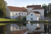 Edificios con vistas a las tranquilas aguas del estanque de Vihula Manor, Vihula, Estonia - foto de stock