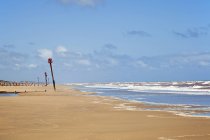 Playa de arena con rompeolas en la distancia - foto de stock