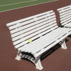 Теннисные корты со скамейками с желтым теннисным мячом на солнце — стоковое фото