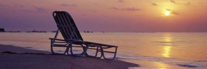 Beach lounger on sand by water at sunrise, Playa del Carmen, Quintana Roo, Mexico — Stock Photo
