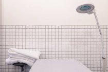 Escritório esteticista com cama, lâmpada e toalhas — Fotografia de Stock