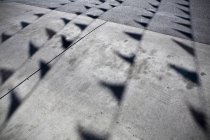 Bandeiras lançando sombras no piso de concreto no estacionamento — Fotografia de Stock