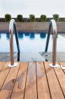 Resort swimming pool with wooden flooring and railings — Stock Photo