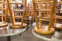 Сидячие стулья, сложенные на круглых столах в помещении — стоковое фото