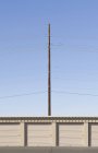 Power lines and pole over bay doors against blue sky — Stock Photo