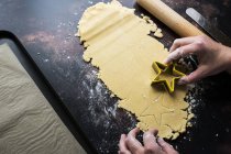 High angle close-up of cook cutting out star-shaped cookies from cookie dough. — Stock Photo
