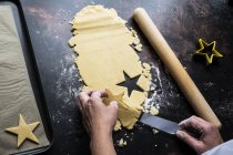 Alto ângulo close-up de cozinhar levantar cortar biscoitos em forma de estrela na assadeira com faca de paleta . — Fotografia de Stock
