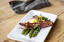Plan rapproché grand angle d'une assiette d'asperges vertes avec bacon croustillant et sauce hollandaise . — Photo de stock