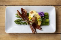 High angle close-up of plate of green asparagus with crispy bacon and Hollandaise Sauce. — Stock Photo